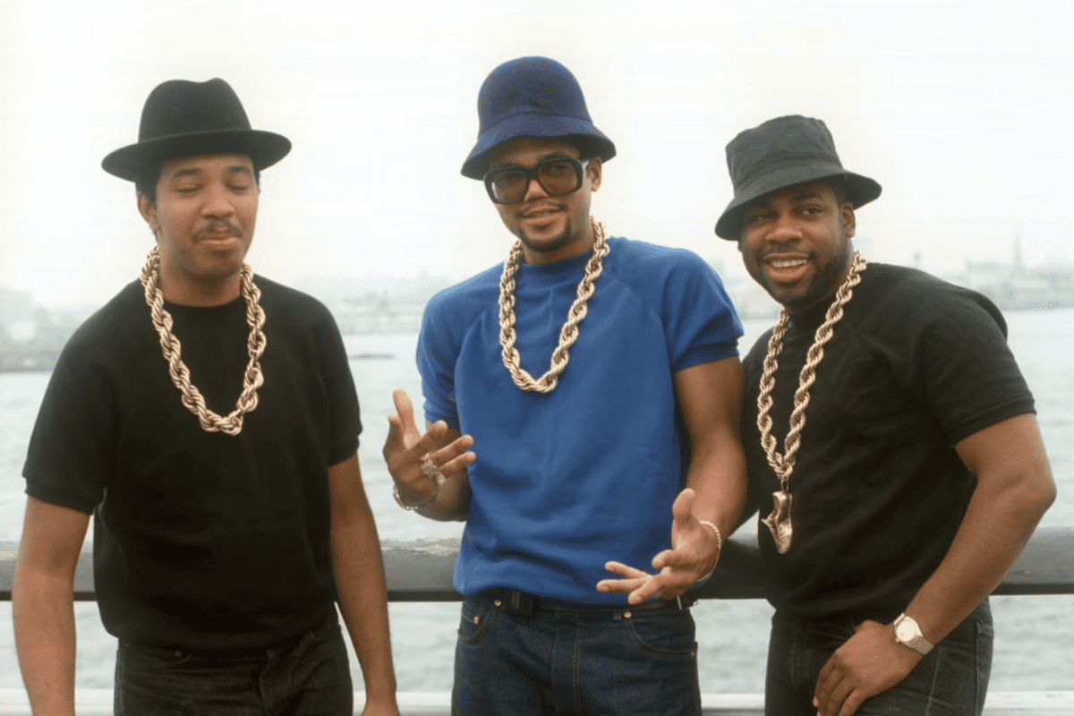 Grupo de rap vistiendo prendas oversize y cadenas doradas