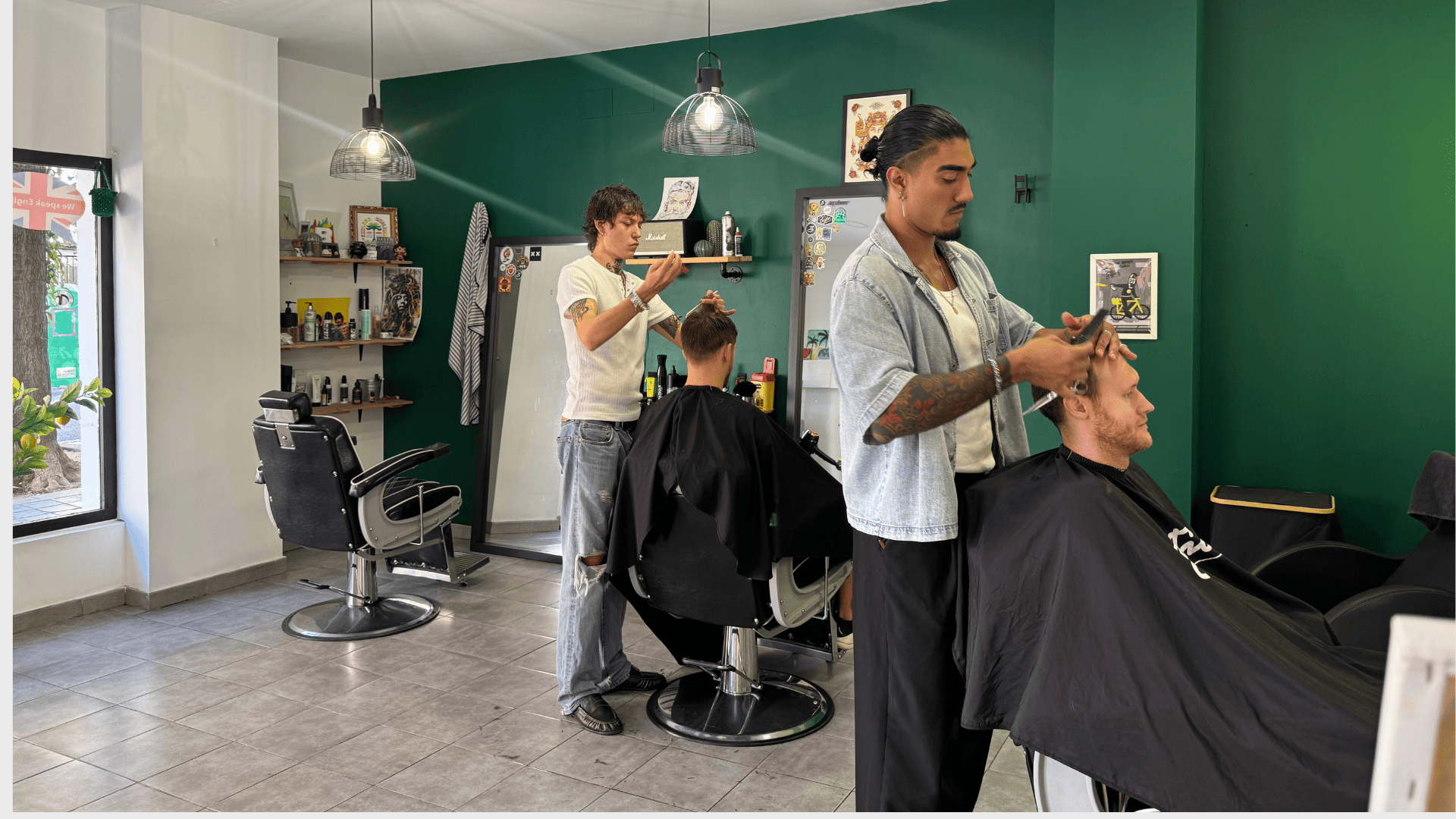Dos barberos cortando el pelo a clientes en Bastián Barber, barbería del Cabanyal en Valencia