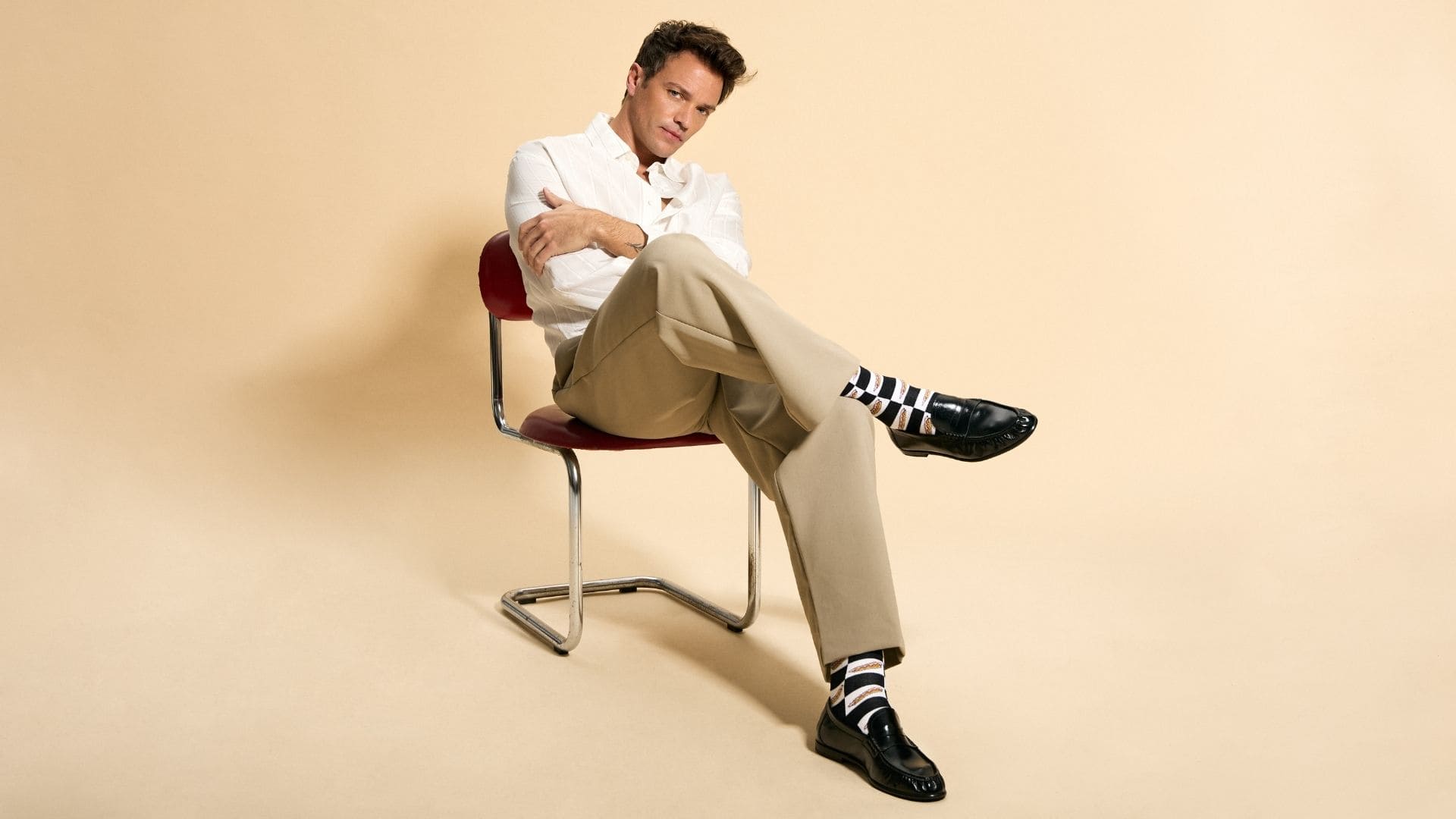 Look masculino de sastrería combinando pantalón beige, mocasines negros y calcetines de diseño geométrico BESOCKS