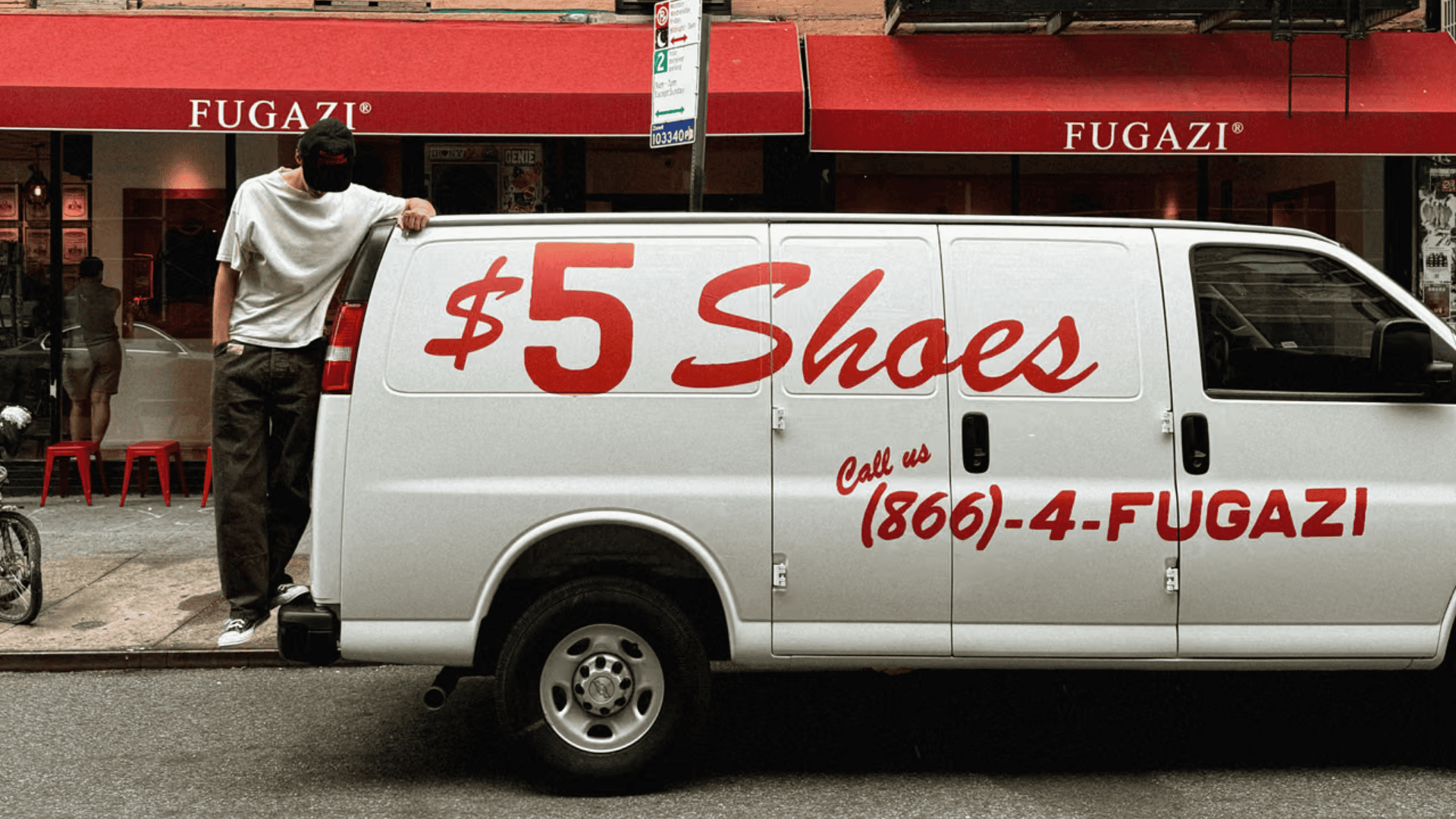 Furgoneta blanca de la marca Fugazi anunciando zapatillas a 5 dolares frente a su tienda
