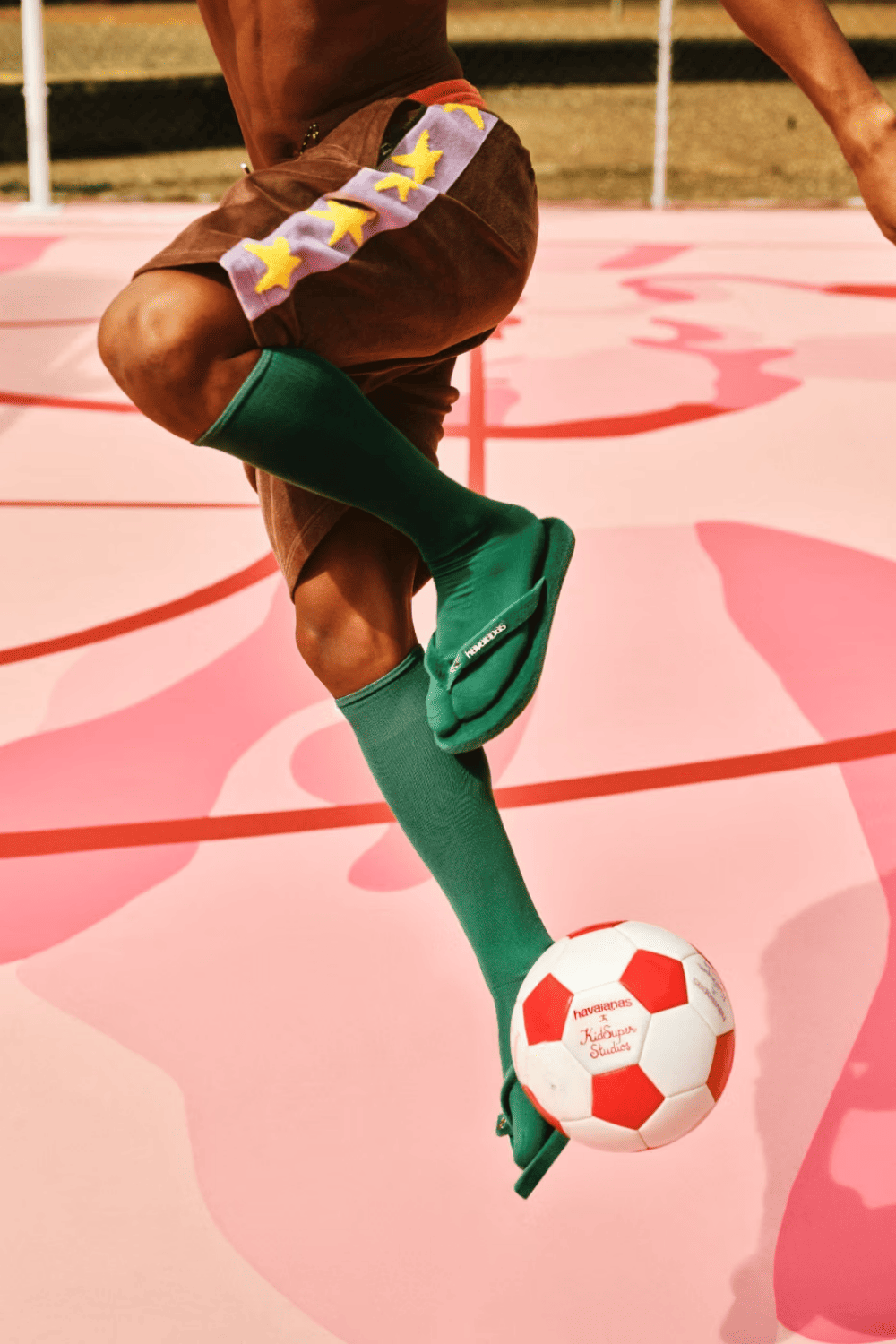 Escena de la campaña Havaianas x KidSuper con la gym sack co-branded y dos pares de sandalias asomando en los bolsillos traseros de un pantalón