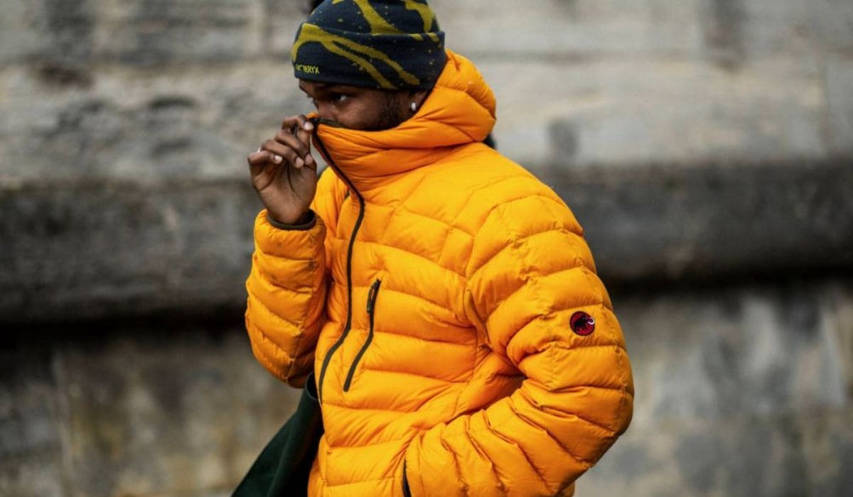 Hombre con chaqueta acolchada naranja estilo outdoor en entorno urbano