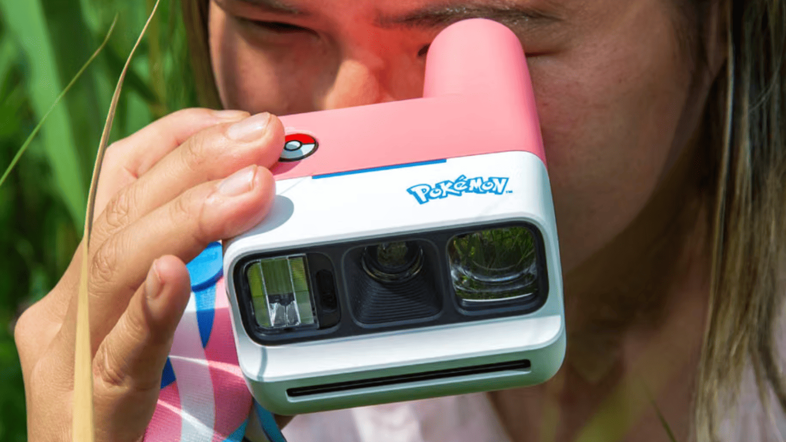 Primer plano de una persona disparando la cámara instantánea Polaroid y Pokémon rosa y blanca edición Sylveon